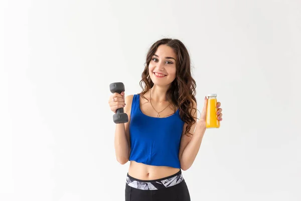 Sport, stile di vita sano, concetto di persone - giovane donna con un manubrio in mano e una bottiglia di succo in un'altra mano — Foto Stock