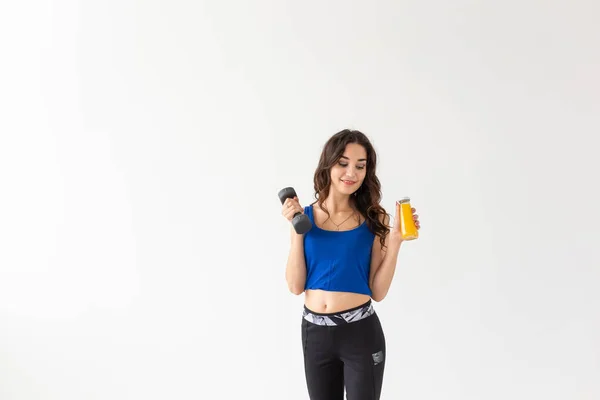 スポーツ、健康なライフ スタイル、人コンセプト - 彼女の手とコピー領域と白い背景の上に別の手でジュースの瓶にダンベルを持つ若い女性 — ストック写真