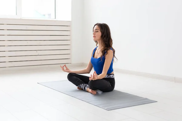 Concepto de yoga, deporte, relax y personas: mujer joven practicando yoga en interiores —  Fotos de Stock