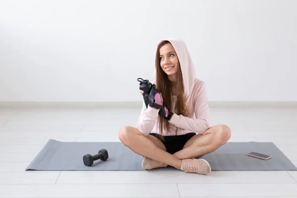 Estilo de vida saludable, personas y concepto de deporte - Mujer sonriente sentada en la esterilla de yoga y agua potable después del entrenamiento duro — Foto de Stock