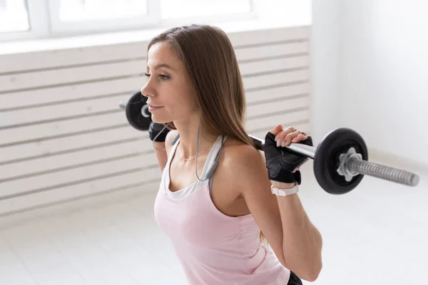 Fitness, sport, concetto di persone - giovane donna in tuta sportiva, i guanti si accovacciano con il bar — Foto Stock