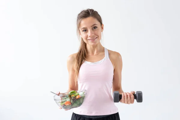 Esporte, estilo de vida são, conceito de pessoas - mulher morena jovem com salada e um halteres. Ela está sorrindo e desfrutando do estilo de vida saudável — Fotografia de Stock