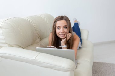 Teknolojileri, serbest ve insanlar kavramı - kanepede dizüstü bilgisayar ile yalan ve kameraya bakarak Genç ve güzel kadın