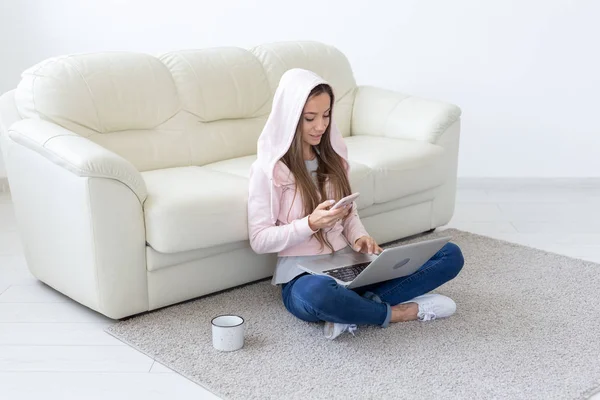 Freelance, concept de liberté et de personnes - Jeune femme avec une tasse de boisson chaude assise sur le sol et travaillant sur un ordinateur portable à la maison — Photo