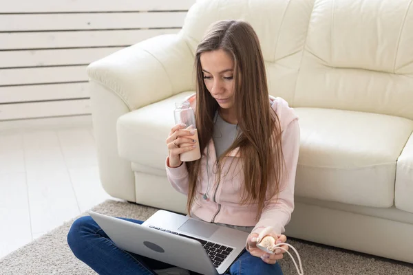 Technologies, freelance et concept de personnes - jeune femme travaillant à la maison, elle boit de l'eau sur le sol, bavarde dans un ordinateur portable — Photo