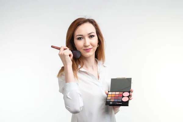 Attraktive Visagistin oder koreanische Visagistin mit einem Make-up-Pinsel und einer Palette von Lidschatten auf weißem Hintergrund — Stockfoto