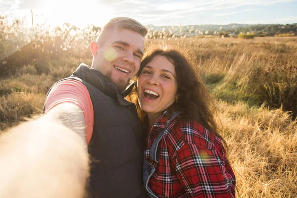 Travel, holidays and nature concept - Happy couple taking a selfie at a field — Stock Photo, Image