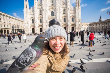 Kış seyahat, tatil ve kuşlar kavramı - genç mutlu kadın turist Milano'da ünlü Duomo Katedrali önünde selfie fotoğraf yapma komik güvercinler ile.