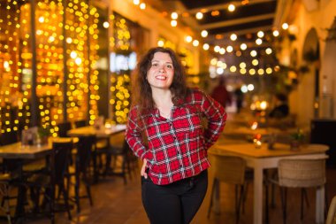 Gece hayatı, insanlar ve eğlence kavramı - güzel genç kadın sokakta parlak restoran yakınında gece poz veriyor