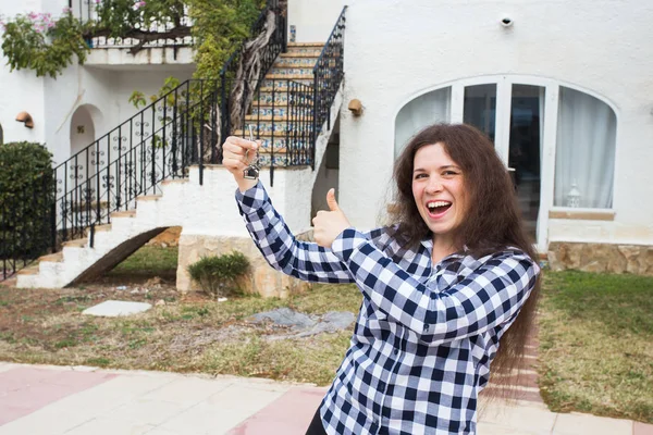 Nieuwe woning, huis, eigendom en huurder - grappige jongedame toets ingedrukt te houden tegenover haar nieuwe huis na het kopen van onroerend goed — Stockfoto