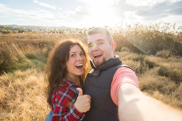 Koncepcja podróży, wakacji i wczasów - szczęśliwa para zabawy biorąc selfie na tle na pole i zachód słońca — Zdjęcie stockowe
