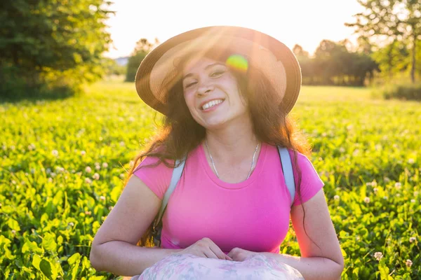 Letní a příroda koncept - zdravá usměvavá mladá žena leží na zelené trávě polní kvítí. Je veselá a šťastná — Stock fotografie