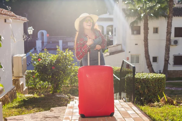 Viajes, vacaciones y el concepto de la gente - Feliz mujer risueño turista con maletas de pie sobre el fondo del hotel — Foto de Stock