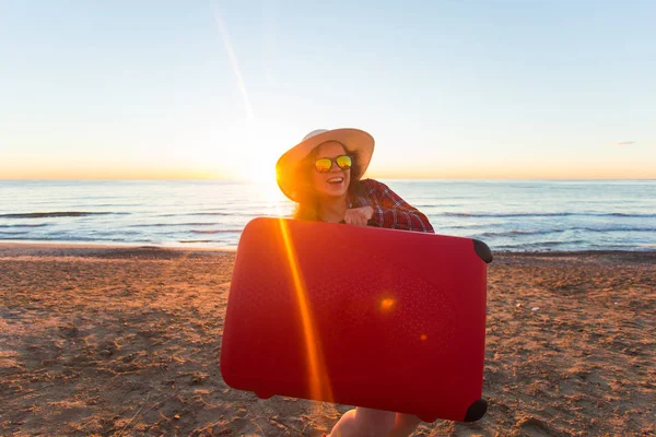 Concepto de vacaciones, viajes y turismo - Hermosa mujer con maleta roja sobre fondo de playa de arena — Foto de Stock