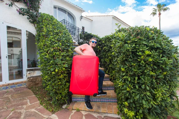 Reizen, toerisme en mensen concept - gelukkig man klimmen de trap met rode koffer en glimlachen — Stockfoto