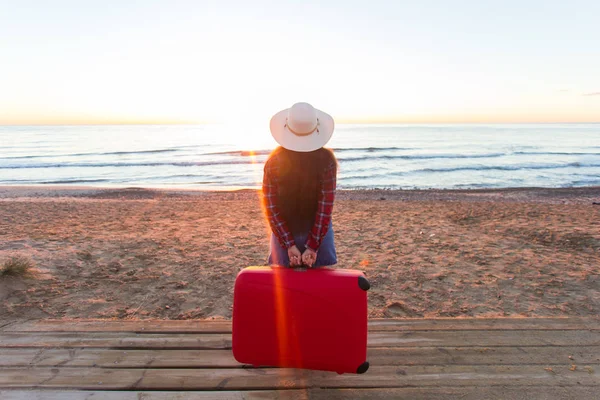 Concetto di viaggio, vacanza e vacanza - Vista posteriore della giovane donna che tiene la valigia sulla spiaggia — Foto Stock