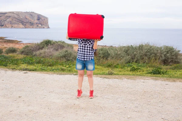 Concepto de vacaciones, viajes y turismo - mujer joven con maleta roja sobre el fondo del mar — Foto de Stock