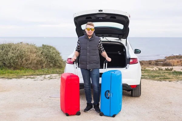 Muž stojící za auto s úsměvem a chystá se jít. Mladí se smíchem mle stojící vedle otevřeného kufru auta. Letní výlet — Stock fotografie