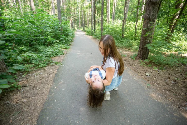 Concepto de familia y naturaleza: una joven atractiva se divierte con su hija pequeña en el parque —  Fotos de Stock