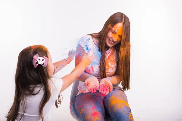 Família, festival de holi e feriados conceito - Mãe e sua filhinha coberta com pó de cor sorrindo sobre fundo branco — Fotografia de Stock