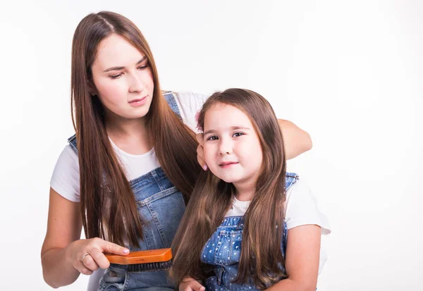 Concepto de familia, maternidad y padres: madre peinando el cabello de sus hijas pequeñas aisladas sobre un fondo blanco —  Fotos de Stock