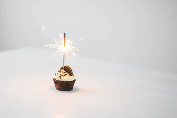 Conceito de comida e feriado - Cupcake de aniversário com sparkler sobre fundo branco com espaço de cópia — Fotografia de Stock