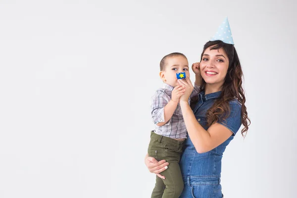 Personas, niños y concepto de vacaciones - Madre encantadora sostiene a su hijo con gorra de cumpleaños sobre fondo blanco con espacio para copiar — Foto de Stock