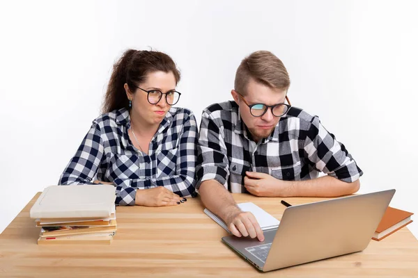 Menschen und Bildungskonzept - zwei verdutzte Studenten in karierten Hemden sitzen am Tisch — Stockfoto