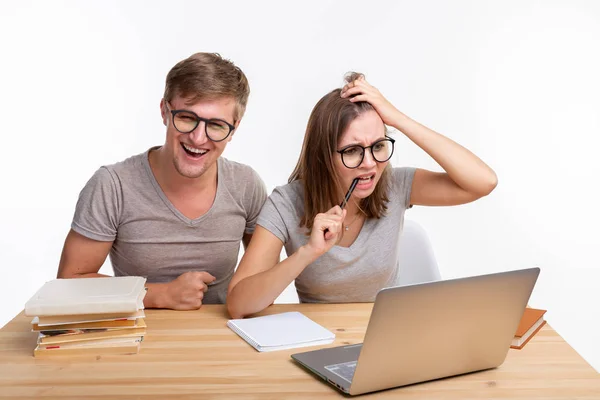 Menschen und Bildungskonzept - zwei fröhliche lustige Studenten sitzen am Holztisch mit Laptop und Büchern — Stockfoto