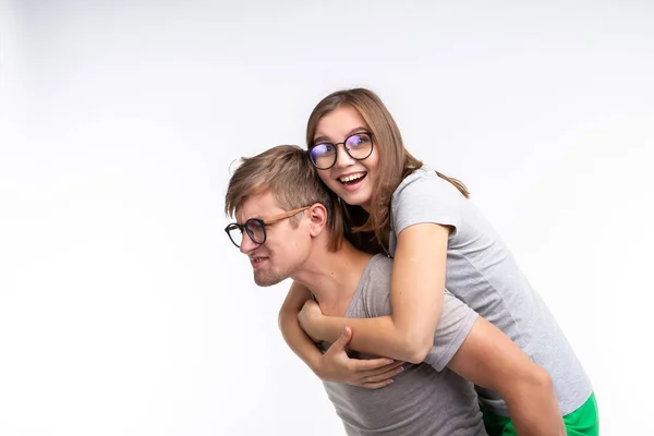 La educación, la gente divertida y el concepto de broma - una mujer joven saltó sobre una espalda de hombre. Son felices. — Foto de Stock