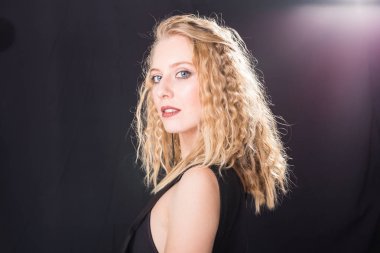 Moda ve model kavramı - kopya alanı ile beyaz bir duvara poz siyah elbiseli güzel genç seksi sarışın kadın portresi