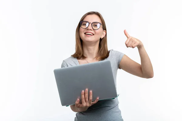 Concepto de personas y educación: atractiva estudiante que sostiene una computadora portátil y muestra el pulgar hacia arriba sobre el fondo blanco — Foto de Stock