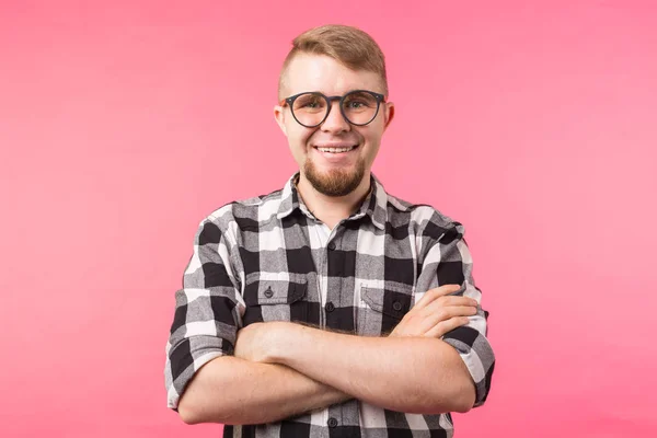 Retrato de un hombre barbudo sonriente con anteojos mirando a la cámara aislada sobre fondo rosa — Foto de Stock