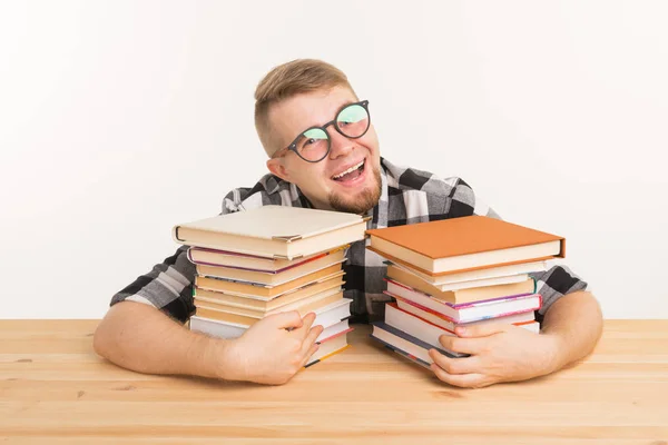 Concepto de personas, conocimiento y educación - Guy sentado abrazando un libro en la mesa de madera — Foto de Stock