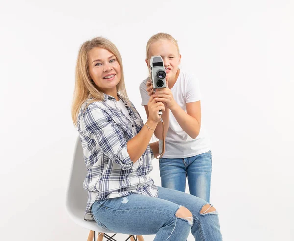 Foto, fotógrafo y concepto de cámara retro - mujer joven y su hija adolescente usando cámara vintage sobre fondo blanco — Foto de Stock