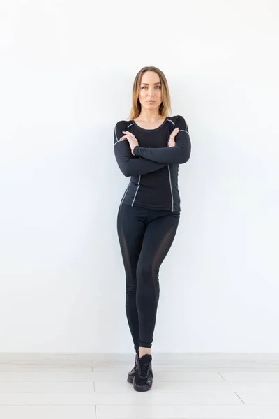 Gente, fitness y deporte concepto- Hermosa mujer en forma vestida con ropa deportiva posando sobre fondo blanco —  Fotos de Stock