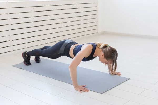 Gente, sano y deportivo concepto- Joven mujer atractiva deportiva haciendo flexiones — Foto de Stock