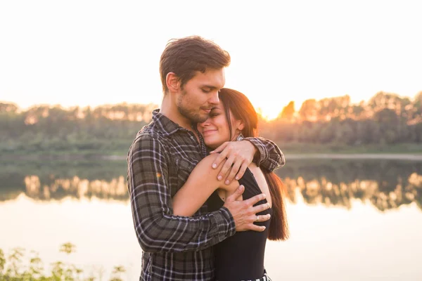 Ρομαντική και άνθρωποι έννοια - νεαρό ζευγάρι αγκάλιασμα μαζί κοντά στο ποτάμι ή λίμνη και απολαμβάνοντας την θερινή ώρα — Φωτογραφία Αρχείου