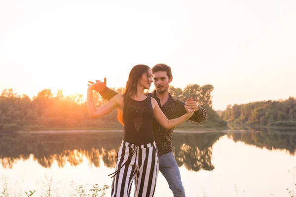 Romantiska, social dans och personer koncept - ungt par dansar en tango eller bachata nära sjön — Stockfoto