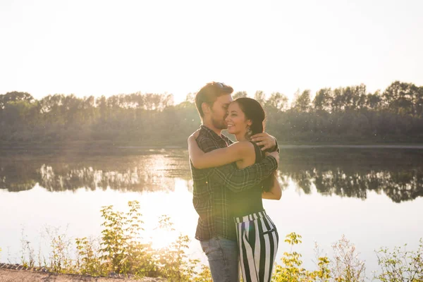 Gente, amor y concepto de la naturaleza - Retrato de una pareja joven y hermosa abrazándose mientras están de pie sobre el fondo de la naturaleza — Foto de Stock