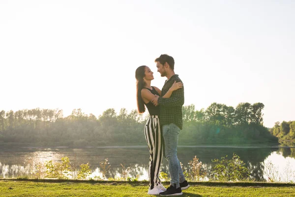 Amor, romântico, natureza, conceito de pessoas - jovem casal encantador olhando um para o outro e abraçando perto do lago — Fotografia de Stock