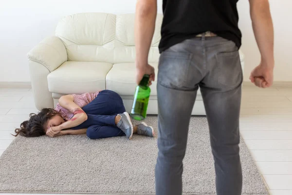 Domácí násilí, alkoholu a zneužívání koncept - opilý muž s lahví zneužívá svou ženu, jak leží na podlaze — Stock fotografie