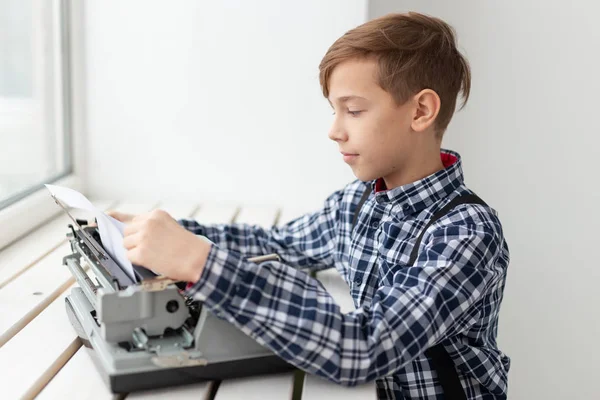 Persone, bambini e concetto di stile - ragazzo con vecchia macchina da scrivere nera su sfondo bianco — Foto Stock