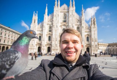 Kış seyahat, tatil ve kuşlar kavramı - yakışıklı erkek turist Milano'da ünlü Duomo Katedrali önünde selfie fotoğraf yapma komik güvercinler ile.