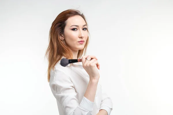 Beauty Make-up Artist. Nahaufnahme koreanische schöne junge Frau hübsch lächelnd hält Make-up-Pinsel auf weißem Hintergrund. — Stockfoto