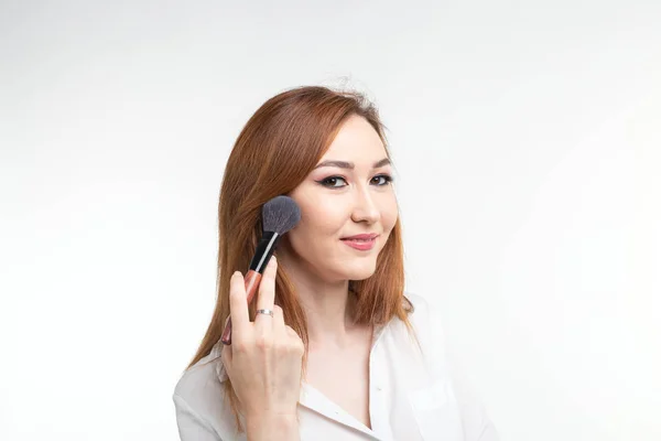 Visagistin, Schönheits- und Kosmetikkonzept - koreanische Visagistin mit Make-up-Pinseln auf weißem Hintergrund — Stockfoto