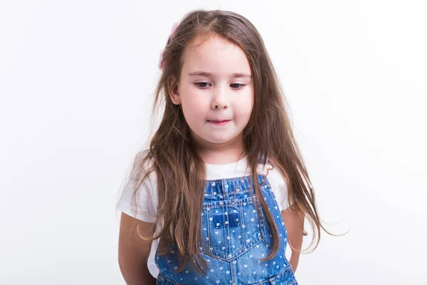 Adorable niña aislada sobre fondo blanco. Niño sonriente en overoles de mezclilla . — Foto de Stock