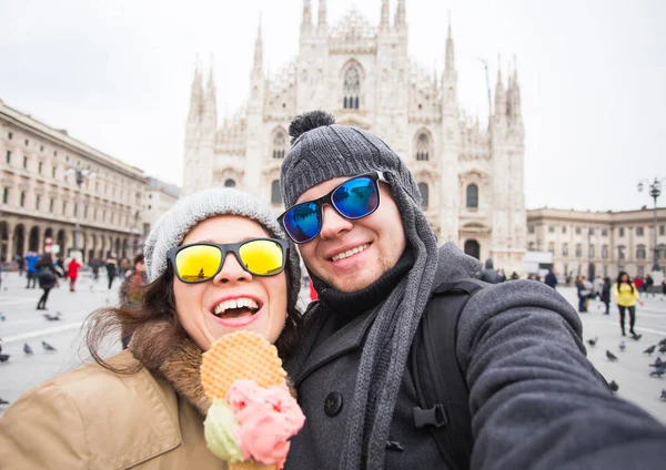 Travel in winter concept - Young and happy tourist making selfie photo in front of the famous Duomo cathedral in Milan. Happy vacations in Milan.