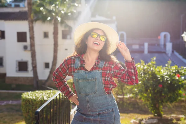 Reizen, zomer en vakantie concept - gelukkige jonge vrouw in hoed lachend over de achtergrond van het hotel — Stockfoto