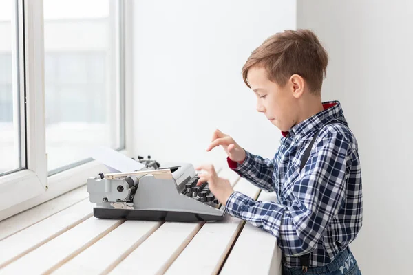 Persone, bambini e concetto di stile - ragazzo con vecchia macchina da scrivere nera su sfondo bianco — Foto Stock